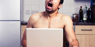 Mann masturbiert vor Laptop am Küchentisch