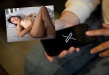 Frau hält Smartphone mit X-App daneben ein Bild von einer Frau nackt im Bett