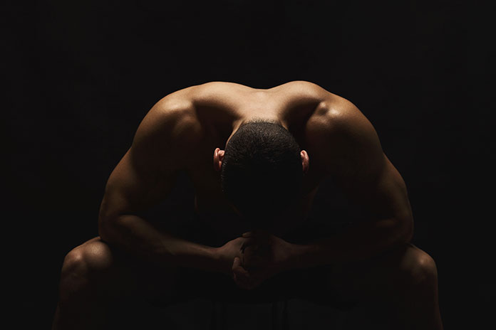 Sitzender Mann beugt seinen Kopf nach unten