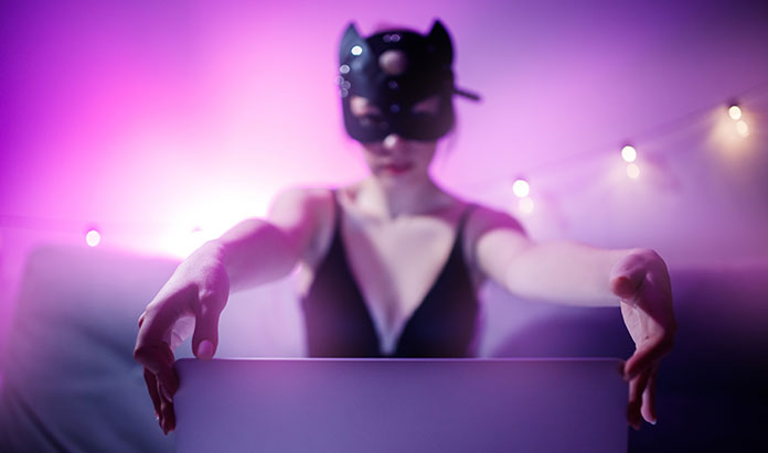 Internet Webcam Model in BDSM Katzenmaske sitzt vor Laptop