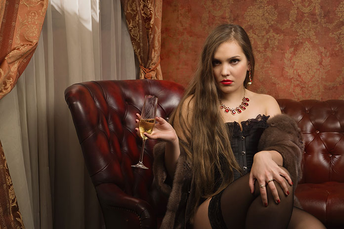 Frau auf Ledercouch hat Sektglas in der Hand